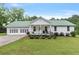 Charming single-story home featuring a green metal roof, white siding, attached garage and a cozy front porch at 11415 Hutcheson Ferry Rd, Chattahoochee Hills, GA 30268