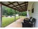 Covered porch with black Adirondack chairs overlooking the backyard at 11415 Hutcheson Ferry Rd, Chattahoochee Hills, GA 30268