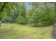 Grassy backyard, lush landscaping, mature trees and side view of retaining wall at 1265 Woodland Se Ave, Atlanta, GA 30316