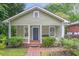 Charming bungalow with a covered front porch, blue door, and lush landscaping at 1265 Woodland Se Ave, Atlanta, GA 30316