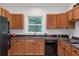 Kitchen with wood cabinets, stainless steel sink below window, and black appliances at 1265 Woodland Se Ave, Atlanta, GA 30316