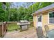 Outdoor back deck with a gas grill, surrounded by a lush green backyard and forest at 410 Lima Ct, Woodstock, GA 30188