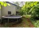 Backyard view featuring a trampoline surrounded by lush greenery and the house's back exterior at 410 Lima Ct, Woodstock, GA 30188