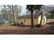 Back exterior of yellow single-story home with brick chimney in an undeveloped yard at 4622 Dogwood Rd, Pine Lake, GA 30072