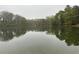 Overlooking a serene pond with vibrant trees reflecting on the water's surface under an overcast sky at 4622 Dogwood Rd, Pine Lake, GA 30072