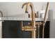 Close up of a gold water fixture in a modern bathroom with marble countertop and black cabinetry at 100 Sheridan Dr, Atlanta, GA 30305