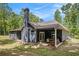 Charming rear exterior featuring a covered patio, wood pile, and neatly manicured lawn at 30 Deer Creek Ct, Moreland, GA 30259