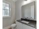 Stylish half bathroom with a dark granite countertop, modern mirror, and crisp white cabinets at 7625 Breeze Bay Rd, Cumming, GA 30041