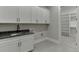Bright laundry room with gray countertop, white cabinets, black hardware, and a doorway leading to an open walk-in closet at 7625 Breeze Bay Rd, Cumming, GA 30041