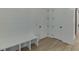 A mudroom area with wood floors, storage bench, white shiplap walls, and closet doors for an organized entryway at 7625 Breeze Bay Rd, Cumming, GA 30041