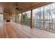 Spacious covered patio featuring a brick fireplace, wood-beamed ceiling, and a ceiling fan overlooking the lake at 7625 Breeze Bay Rd, Cumming, GA 30041