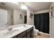 A full bathroom featuring dual sinks, large mirror, ceramic floors and a shower/tub combo with dark curtain at 85 Foxgrove Cv, Covington, GA 30014