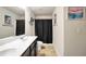 Full bathroom featuring dual sinks, large mirror, ceramic floors and a shower/tub combo with dark curtain at 85 Foxgrove Cv, Covington, GA 30014