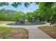 Community playground with slides and climbing structures, surrounded by a cushioned surface and a paved walkway at 85 Foxgrove Cv, Covington, GA 30014