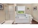 Bright bathroom features a white tiled tub and shower surround, and wood-look flooring at 5404 Trumpet Vine Se Trl, Mableton, GA 30126
