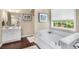 Bright bathroom featuring a large soaking tub, dark wood floors, and a white vanity with marble countertop at 5404 Trumpet Vine Se Trl, Mableton, GA 30126