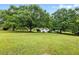 Sprawling yard with mature trees and a home in the distance at 1430 Mineral Springs Rd, Hoschton, GA 30548