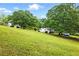 Gently sloping yard with mature trees and a home in the distance at 1430 Mineral Springs Rd, Hoschton, GA 30548