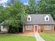 Charming brick home with an inviting red door, green shutters and mature trees at 2458 Zachary Woods Dr, Marietta, GA 30064