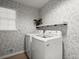 Laundry room with modern white washer and dryer, floral wallpaper, and natural light from the window at 2458 Zachary Woods Dr, Marietta, GA 30064