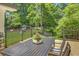 Outdoor deck with table and chairs offers scenic views of the manicured backyard and wooded surroundings at 1343 Peachtree Battle Nw Ave, Atlanta, GA 30327