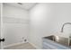 Efficient laundry room featuring stainless steel sink, white cabinets, and a wire rack for organized storage at 5346 Kelleys Mill Cir, Stone Mountain, GA 30088