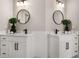 This bathroom shows a double vanity with white cabinets, dark hardware, round mirrors and modern black faucets at 939 Whistler Ln, Canton, GA 30114