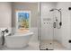 A soaking tub next to a glass enclosed shower showcasing white tile and black hardware with a view at 939 Whistler Ln, Canton, GA 30114