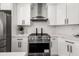Close up of a modern kitchen with white cabinets, stainless steel range hood, and marble-style countertops at 939 Whistler Ln, Canton, GA 30114