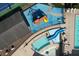 Aerial view of a pool, playground, and tennis courts with tables, umbrellas, lounge chairs, and a slide at 940 River Valley Dr, Dacula, GA 30019