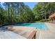 Gorgeous view of a long in-ground pool surrounded by nature, with lounge seating nearby at 227 Eton Ct, Mableton, GA 30126
