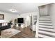 Open living space with hardwood floors, grey sofa, television, and staircase at 6900 Roswell Rd # 3N, Atlanta, GA 30328