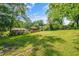 Expansive backyard with lush green grass, mature trees, and outbuildings with a blue sky at 765 Shellnut Dr, Forest Park, GA 30297