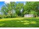 Large grassy backyard with mature trees and a storage shed for ample outdoor space at 765 Shellnut Dr, Forest Park, GA 30297