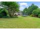Spacious backyard with lush lawn, a pool, mature trees, and a trampoline at 100 Braxton Way, Roswell, GA 30075