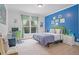 Bright bedroom with a blue accent wall, complemented by a large window and a cozy study area at 100 Braxton Way, Roswell, GA 30075