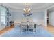 Elegant dining room boasting a chandelier, hardwood floors, large window and soft blue walls at 100 Braxton Way, Roswell, GA 30075