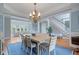 Open-concept dining area with blue walls, hardwood floors, chandelier and staircase leading into living area at 100 Braxton Way, Roswell, GA 30075
