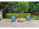 Cozy fire pit area with stone surround, surrounded by lush landscaping and two blue Adirondack chairs at 100 Braxton Way, Roswell, GA 30075
