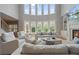 Bright, large living room featuring floor-to-ceiling windows, a fireplace, and cozy seating at 100 Braxton Way, Roswell, GA 30075