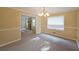 Open dining area with neutral carpet, large window, and classic chandelier fixture at 1003 Wiley Bridge Rd, Woodstock, GA 30188