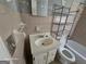 Vintage pink tiled bathroom with sink, toilet and metal shelving unit at 1243 Hill Nw St, Conyers, GA 30012