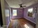 View of bedroom with peeling wood floors, light purple walls, white trim, and a three blade ceiling fan at 1243 Hill Nw St, Conyers, GA 30012