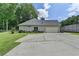 Rear view of home features large driveway, three car garage, fenced perimeter, and lawn at 1815 Sharon Rd, Cumming, GA 30041