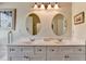 Bright bathroom features a double vanity with white cabinets and oval mirrors and decorative light fixture at 1815 Sharon Rd, Cumming, GA 30041