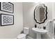 Elegant powder room featuring a pedestal sink, decorative mirror, and stylish wall art at 6763 Encore Blvd, Atlanta, GA 30328