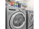 Modern laundry room with front-loading washer and dryer; features storage shelves and efficient appliances for convenience at 1326 Castleberry Dr, Buford, GA 30518