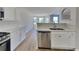 Open kitchen with stainless steel dishwasher, white cabinets, and quartz countertops at 5052 Hickory Cir, Ellenwood, GA 30294