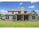 Back of house with a covered patio area for entertaining and a well-manicured lawn at 161 Archstone Sq, Mcdonough, GA 30253