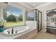 Bright bathroom featuring a large soaking tub, glass enclosed shower, and a view of the backyard at 161 Archstone Sq, Mcdonough, GA 30253